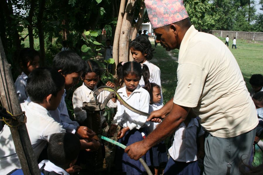 Pedellen Raju hjælper børnene med at få vasket hænder